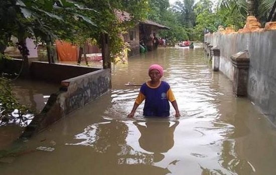 Seorang warga di Kecamatan Binjai Selatan, Kota Binjai, Sumatera Utara saat melintasi banjir, Jumat (26/11/2021) siang.